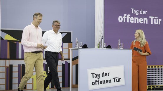 Staatsminister Weimer und Reporter-Slam-Gr&uuml;nder Jochen Markett im Gespr&auml;ch mit Olga Patlan aufr der B&uuml;hne im Ehrenhof