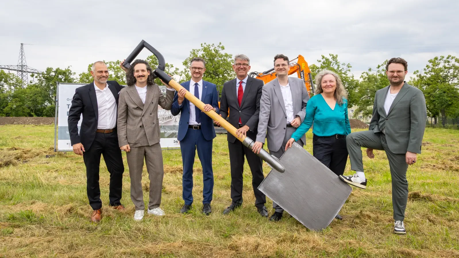 Gruppenbild auf einer Wiese mit gro&szlig;em Spaten