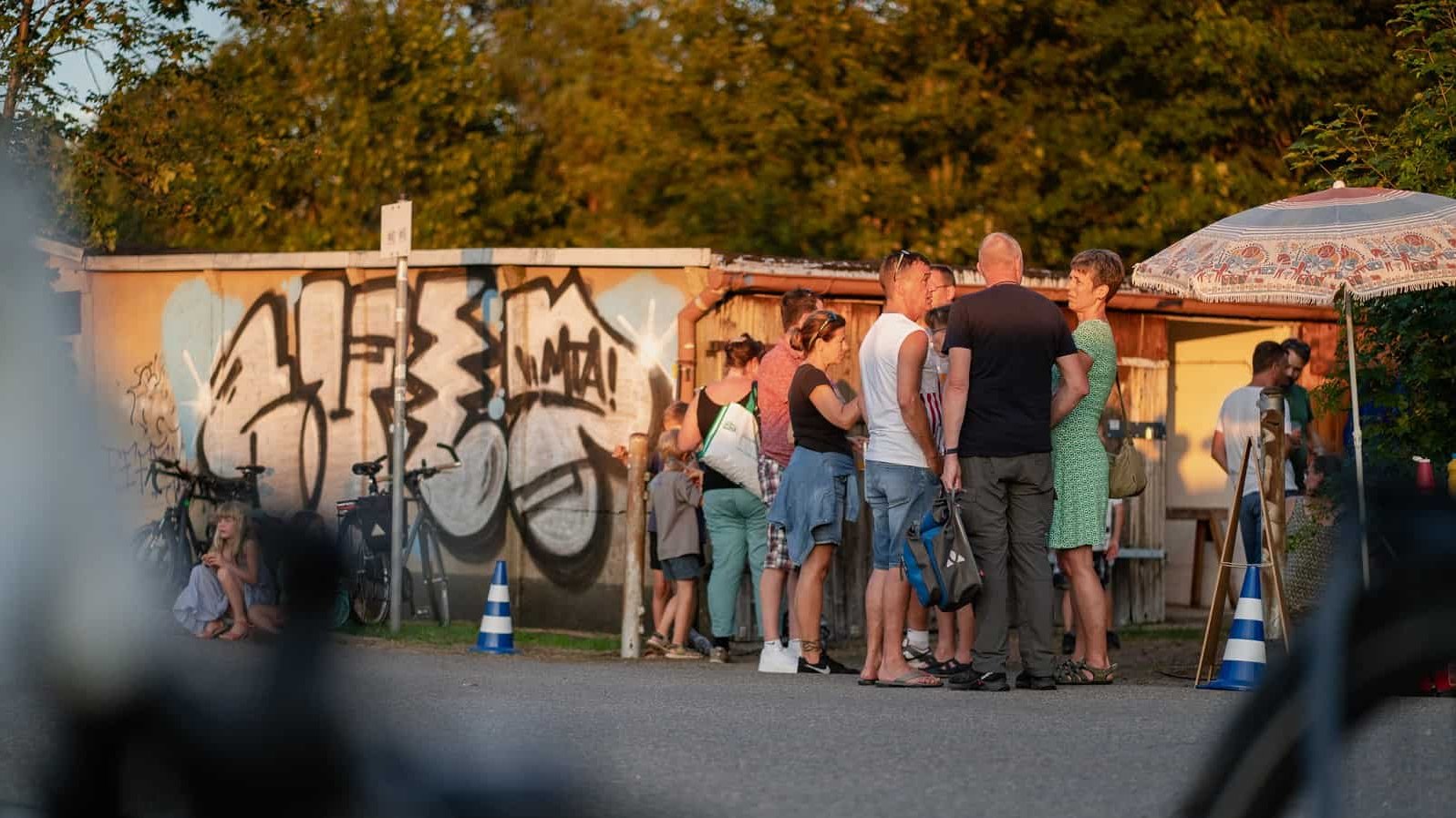 Eine Gruppe von Menschen unterh&auml;lt sich im Garagenhof Harthweg.