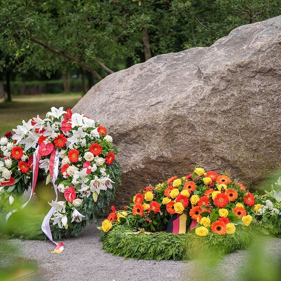 Ensemble aus großem Gedenkstein mit einer Widmungsplatte aus gerostetem Stahl und einem Wildapfelbaum. 