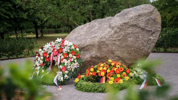 Ensemble aus großem Gedenkstein mit einer Widmungsplatte aus gerostetem Stahl und einem Wildapfelbaum. 