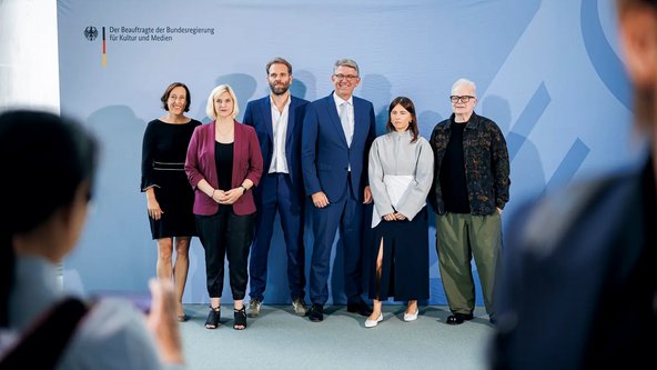 Susanne Dehmel, Mitglied der Gesch&auml;ftsleitung &bdquo;KI & Daten&ldquo; Bitkom,  Verena B&ouml;&szlig;mann, Vorstandsmitglied im Verband unabh&auml;ngiger Musikunternehmer*innen e. V., Florian Dr&uuml;cke, Vorstandsvorsitzender und CEO des Bundesverbandes Musikindustrie, Staatsminister Weimer,  K&uuml;nstlerin Balbina von der Akademie f&uuml;r popul&auml;re Musik und K&uuml;nstler Herbert Gr&ouml;nemeyer bei der Pressekonferenz im Kanzleramt. 