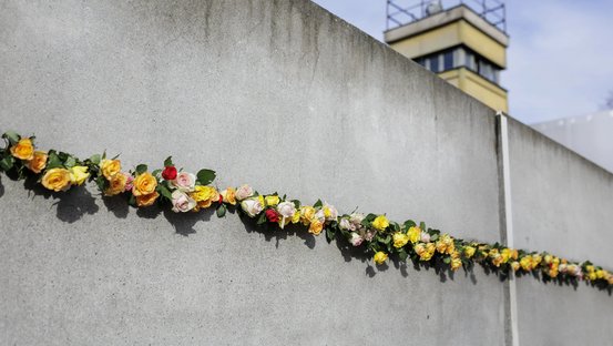Rosen stecken in einem Stück der Berliner Mauer