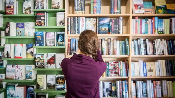 Eine Frau steht vor einem B&uuml;cherregal in einer Buchhandlung