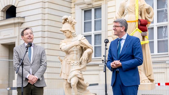 Hartmut Dorgerloh, Generalintendant des Humboldt Forums, und Kulturstaatsminister Wolfram Weimer vor zwei Balustradenfiguren im Humboldt Forum.
