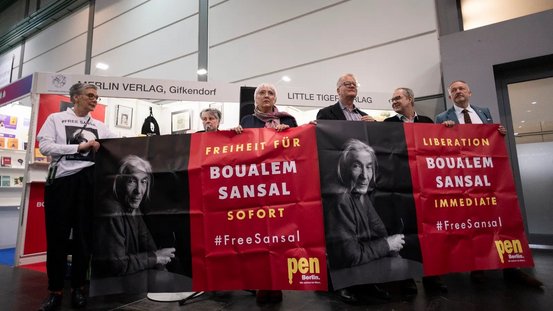 Kulturstaatsministerin Roth hält zusammen mit der Vorsteherin des Börsenvereins Karin Schmidt-Friderichs (links) ein Poster bei der Protestaktion zur Freilassung von Boualem Sansal.