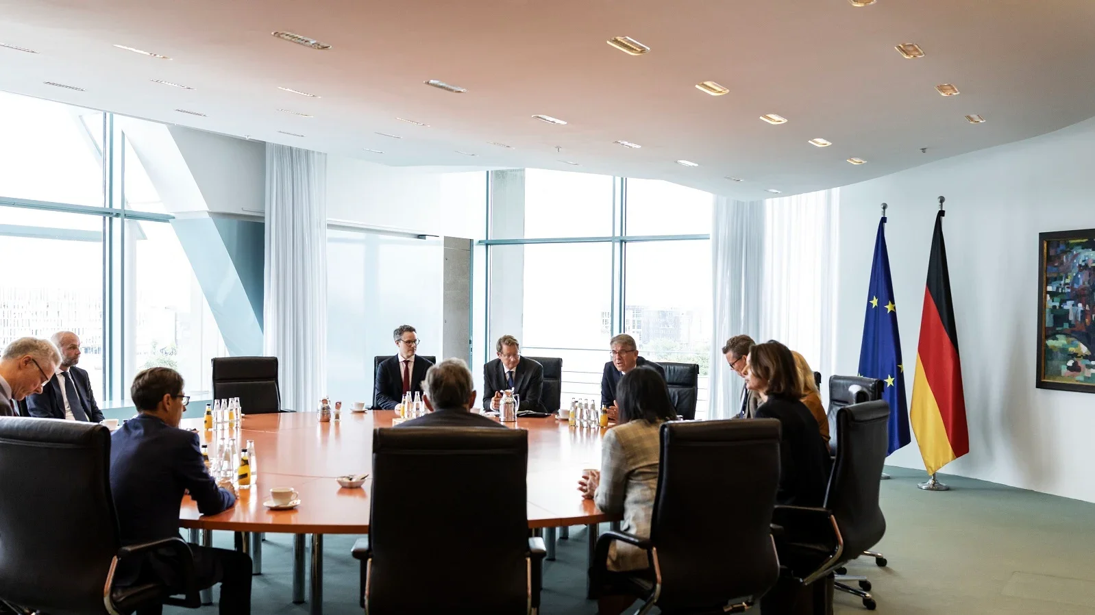 Die Gespr&auml;chsteilnehmerinnen und -teilnehmer sitzen an rundem Tisch im Bundeskanzleramt. 