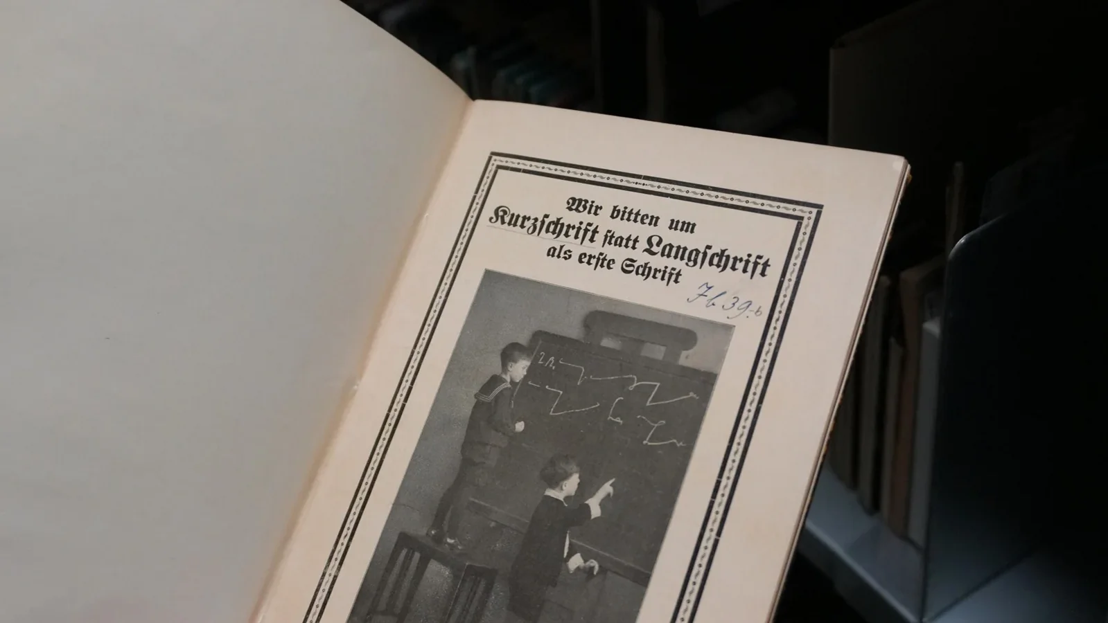 Ein aufgeklapptes historisches Buch zeigt Kinder, die stenografische Zeichen an eine Tafel schreiben 