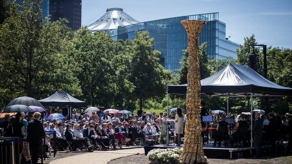 Das Mahnmal im Berliner Tiergarten mit sitzendem Veranstaltungspublikum und Blick auf den Potsdamer Platz