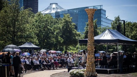 Das Mahnmal im Berliner Tiergarten mit sitzendem Veranstaltungspublikum und Blick auf den Potsdamer Platz