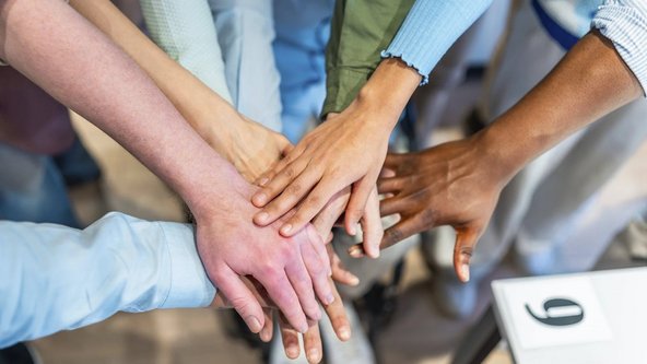 Aufeinandergelegte H&auml;nde symbolisieren Einigkeit und Zusammenarbeit. 