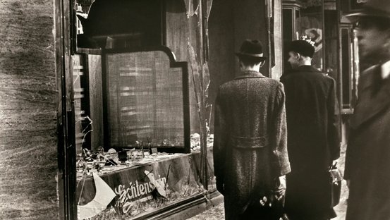 Passanten vor dem zerstörten Schaufenster eines jüdischen Geschäfts in Berlin nach den antisemitischen Ausschreitungen 1938