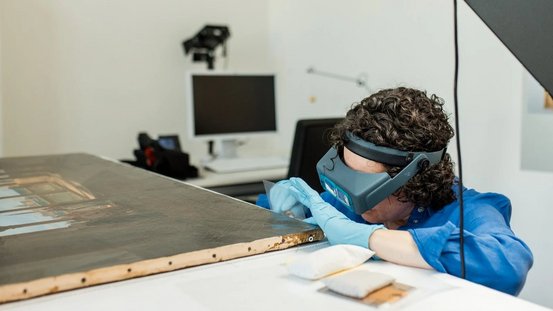 Ein Mitglied des Forschungsteams untersucht ein Gem&auml;lde 