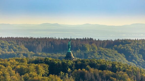 Luftbild des Hermannsdenkmals im Teutoburger Wald vor blauem Himmel.
