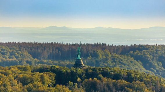 Luftbild des Hermannsdenkmals im Teutoburger Wald vor blauem Himmel.