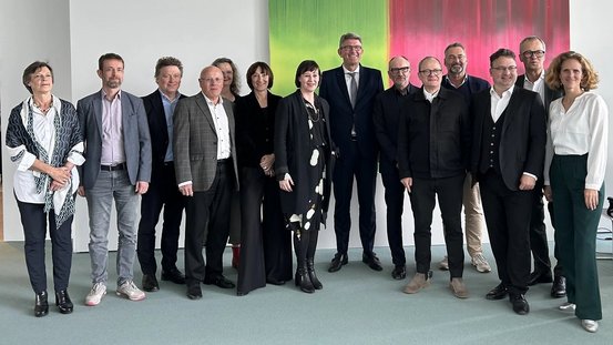 Gruppenfoto von Kulturstaatsminister Weimer mit Opernintendantinnen und -intendanten vor einem Gemälde im Kanzleramt