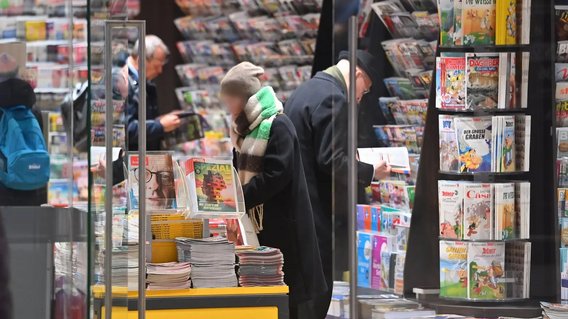 Menschen st&ouml;bern in Zeitschriften und B&uuml;chern in einem Bahnhofskiosk