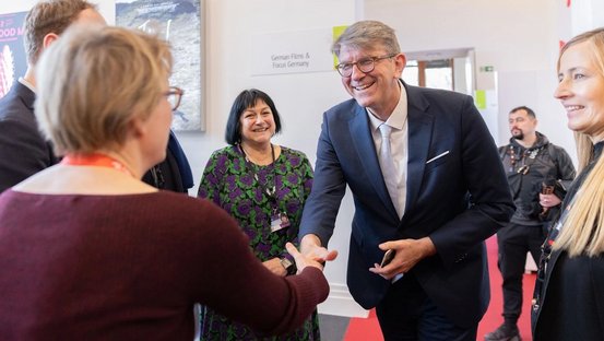 Staatsminister Weimer sch&uuml;ttelt beim Rundgang &uuml;ber den EFM einer Frau die Hand