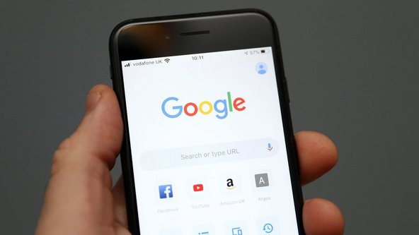 Person hält ein Handy in der Hand, auf dessen Bildschirm Apps wie Google und Facebook zu sehen sind. 