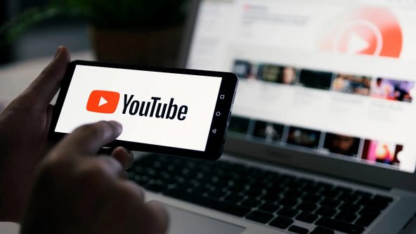 Mann h&auml;lt ein Smartphone mit YouTube-Logo auf dem Bildschirm