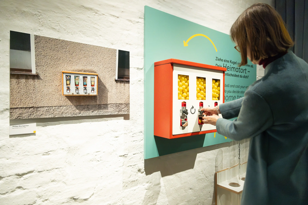 Eine Frau bedient den Kaugummiautomat in der Ausstellung "Ostblicke"