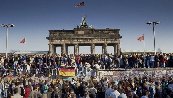 Menschen feiern 1989 den Fall der Mauer am Brandenburger Tor in Berlin