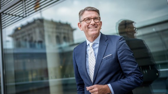 Portr&auml;t von Staatsminister Weimer, im Hintergrund ist die Kuppel des Bundestags zu sehen