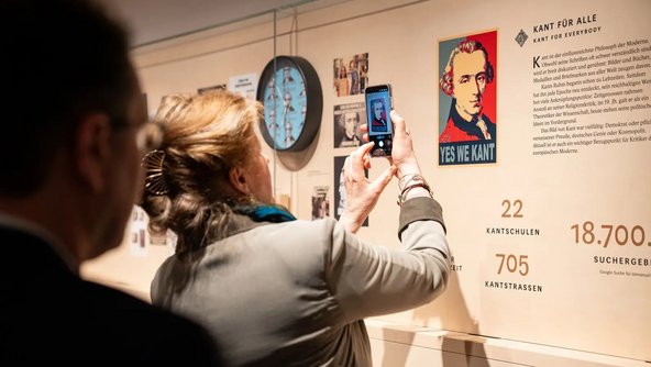 Eine Besucherin fotografiert mit dem Smartphone eine Ausstellungstafel