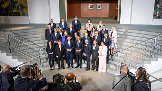 Das Bundeskabinett wird auf der Treppe stehend von Fotografen abgelichtet. 